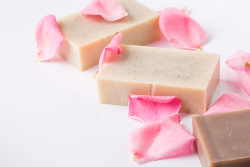 Handmade lotion bars with pink rose petals on white background