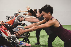 Row of moms working out with exercise balls next to their children in strollers