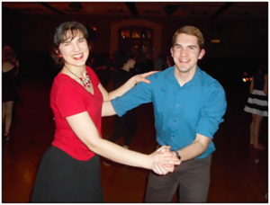 Young woman in red dancing with young man in blue on black background